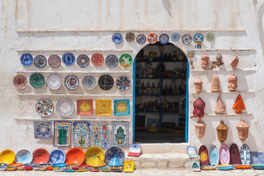 Blick auf einen Shop in einer tunesischen Altstadt mit bunt bemalter Keramik an W&auml;nden und auf dem Boden vor dem Shop